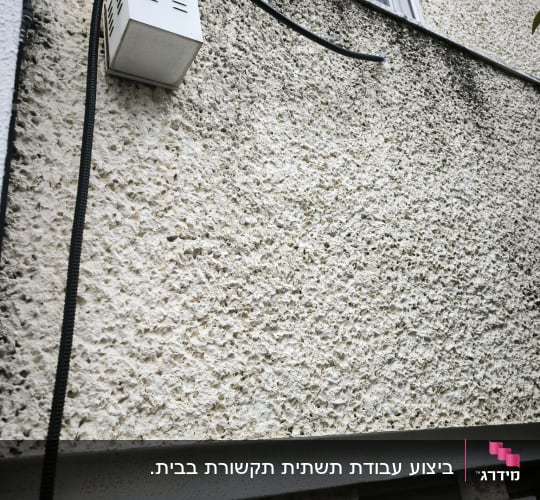 קיר חיצוני עם תיבת תקשורת וכבל מחובר